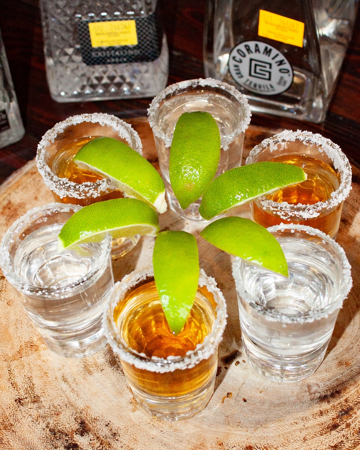 An arrangement of tequila shots with salted rim and limes. 